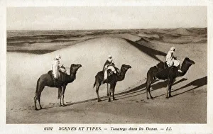 Nomadic Tuaregs riding camels amongst the Saharan Dunes - North Africa Nomadic Tuaregs riding camels amongst the Saharan Dunes - North Africa