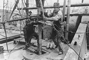 American Oil Industry Prints: Oil field workers adding a length of pipe to drill stream by