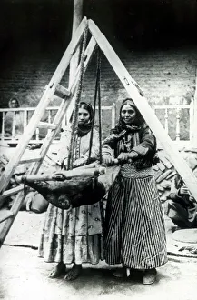 Two Persian women rocking a goatskin to churn milk Two Persian women rocking a goatskin to churn milk
