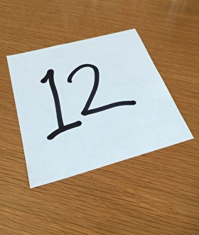 Piece of paper on a desk with a large number 12 Piece of paper on a desk with a large number 12
