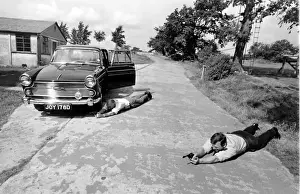 Prints of Two policemen lying on the ground near a car during training at the Police Gun School in North London. Date: 1960s Police Prints: Police Gun School, North London Print 1960s