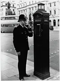Prints of A police officer on the beat south of Pall Mall, central London, reports back to the station using a police call box Police Prints: Print of Policeman and Call Box, Central London