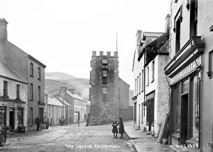 Prints of The Square, Cushendall - a street scene with shop fronts and few people and horse vehicles. (Location: Northern Ireland: County Antrim: Cushendall). Date: circa early 1900s County Antrim Prints: Early 20th Century Print of Cushendall Street Scene