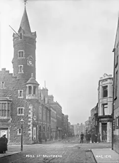 Prints of Mill St. Ballymena - a street scene with clock tower to the left and shop fronts and people. (Location: Northern Ireland: County Antrim). Date: circa early 1900s Map Prints: Early 20th Century Ballymena Street Scene Print