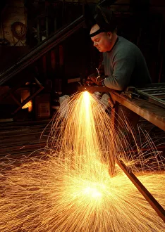 A steelworker makes a shower of sparks in his workshop A steelworker makes a shower of sparks in his workshop