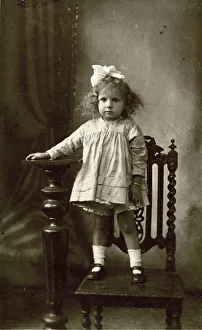 Studio photo of young girl standing on a chair Studio photo of young girl standing on a chair