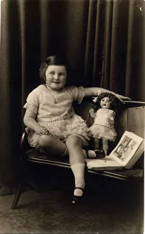 Studio photograph of a little girl pictured with a doll and picture book Studio photograph of a little girl pictured with a doll and picture book