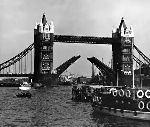 Prints of Tourist vessels such as Skylark London and other ships, passing under Tower Bridge, a bascule bridge which has been raised to let them sail through on the Thames. Date: 1950s Skylark Prints: Tower Bridge Print: 1950s Thames Vessels Passing Under