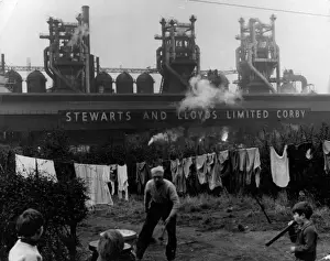 Prints of A washing line and an old man and children in the back garden of a house backing onto the Steward and Lloyds steel mill, Corby, Northamptonshire, England. Date: late 1960s Industrial Prints: Corby Steel Mill Print, Late 1960s
