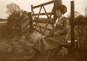 Woman sitting on a stile by a five-bar gate Woman sitting on a stile by a five-bar gate