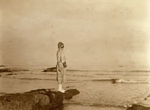 Woman standing on a rock looking out to sea Woman standing on a rock looking out to sea