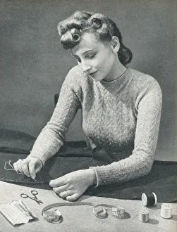 Woman tacking a hem before stitching it Woman tacking a hem before stitching it