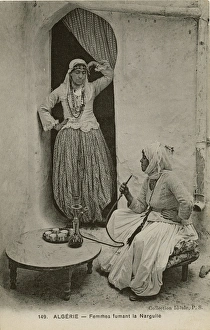 Two women smoke from a hookah pipe, Algeria Two women smoke from a hookah pipe, Algeria