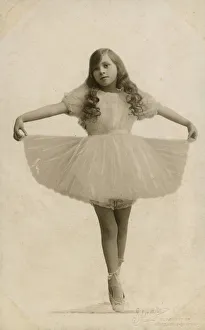 A Young Ballerina with long curled hair on point, holding out her tutu - studio portrait A Young Ballerina with long curled hair on point, holding out her tutu - studio portrait
