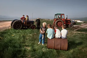 Young children play and men work on tractors - Askam, Cumbria Young children play and men work on tractors - Askam, Cumbria