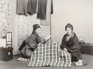 Two young women reading and staying warm, Japan Two young women reading and staying warm, Japan