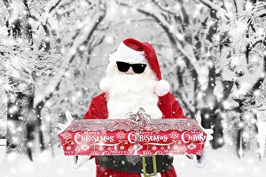 Father Christmas / Santa Claus wearing sunglasses holding Christmas present in winter snow Date: 28-Nov-19 Father Christmas / Santa Claus wearing sunglasses holding Christmas present in winter snow Date: 28-Nov-19