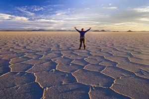 Traveller on Salar de Uyuni - a happy woman with raised hands stands amidst polygonal Traveller on Salar de Uyuni - a happy woman with raised hands stands amidst polygonal