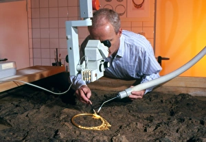 Archaeologist cleaning a golden Celtic necklace Archaeologist cleaning a golden Celtic necklace