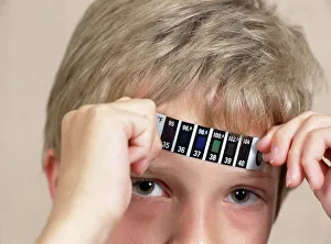 Images Dated 4th June 2003: Boy measuring his temperature with a strip thermometer