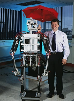 Prints of Darwin Caldwell, Professor of Advanced Robotics at the University of Salford, UK, holding an umbrella over a robotic gorilla he co-created Images Dated 2003 February: Darwin Caldwell with robotic gorilla, Print