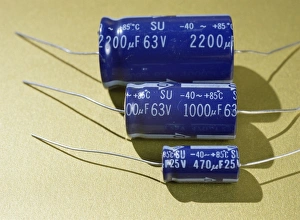 Prints of Three electrolytic capacitors with capacitance values of 2200 microfarads, 1000 microfarads and 470 microfarads. The arrows on the canisters are pointing to the capacitors negative ends Images Dated 2005 June: Three electrolytic capacitors with arrows pointing to negative ends, Print