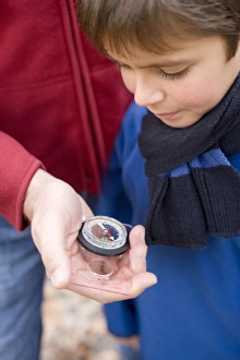 Prints of MODEL RELEASED. Reading a compass. Boy reading a compass being held in his fathers hand Images Dated 2006 March: Father and son reading a compass Print