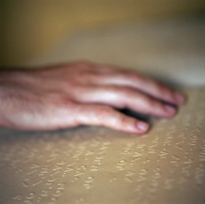 Prints of Moon Braille. Hand of a blind person running over text written in Moon Braille Images Dated 2003 November: Print of a hand running over Moon Braille text