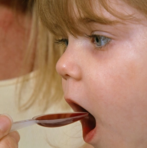 Sick young girl is fed a spoon of medicine Sick young girl is fed a spoon of medicine