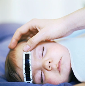 Prints of MODEL RELEASED. Taking babys temperature. Strip thermometer being used to measure the temperature of an 8 month old baby boy while he sleeps Images Dated 2007 May: Baby's temperature measured with a strip thermometer