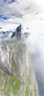 Aerial view of two hikers walking towards the scenic Segla Mountain in a sea of clouds Aerial view of two hikers walking towards the scenic Segla Mountain in a sea of clouds