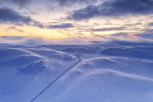 Arctic sunset over Tanafjordveien empty road crossing the snowy mountains after blizzard Arctic sunset over Tanafjordveien empty road crossing the snowy mountains after blizzard