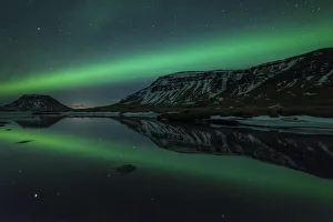 Aurora borealis (Northern Lights) reflected in partially frozen lake, North Snaefellsnes