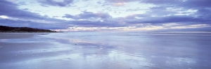 Beach at Alnmouth at dusk with dramatic clouds reflecting in wet sand at low tide Beach at Alnmouth at dusk with dramatic clouds reflecting in wet sand at low tide