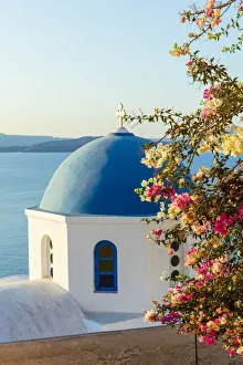 Blue domed white building with colourful flowers in foreground, Oia, Santorini, Cyclades, Greek Islands, Greece, Europe Blue domed white building with colourful flowers in foreground, Oia, Santorini, Cyclades, Greek Islands, Greece, Europe