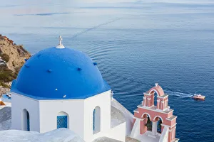 Blue domed white church overlooking boat in Aegean Sea, Santorini, Cyclades, Greek Islands, Greece, Europe Blue domed white church overlooking boat in Aegean Sea, Santorini, Cyclades, Greek Islands, Greece, Europe