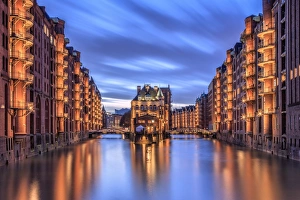 Blue dusk and lights are reflected in Poggenmohlenbrucke with water castle between bridges Blue dusk and lights are reflected in Poggenmohlenbrucke with water castle between bridges