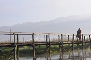 Buddhist monk, walking in the early morning on a wooden walkway, Inle Lake Buddhist monk, walking in the early morning on a wooden walkway, Inle Lake