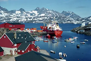 Prints of Cargo ship with freight on the quay, small boats in the harbour, and mountains in the background, at Ammassalik, east Greenland, Polar Regions Greenland Prints: Ammassalik Harbour Print: Cargo Ship with Freight