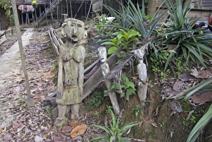 Carved spirits of men and a woman standing at the entrance to Iban tribal longhouse at Carved spirits of men and a woman standing at the entrance to Iban tribal longhouse at