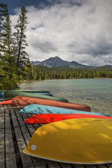 Colourful canoes and kayaks on the bank of Annette Lake with Pyramid Mountain in the background Colourful canoes and kayaks on the bank of Annette Lake with Pyramid Mountain in the background