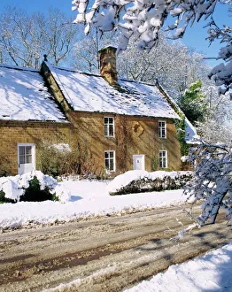 Cotswold farmhouse beside a road covered in snow in winter in England Cotswold farmhouse beside a road covered in snow in winter in England