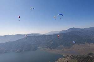 Dozens of paragliders enjoy amazing views of the Himalayas above Phewa Lake, Nepal, Asia Dozens of paragliders enjoy amazing views of the Himalayas above Phewa Lake, Nepal, Asia