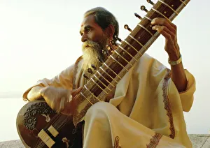 Elderly man playing a sitar by the Ganges (Ganga) River Elderly man playing a sitar by the Ganges (Ganga) River