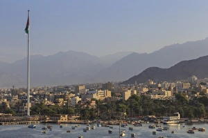 Elevated view of Aqaba seafront with huge Jordanian flag, boats and hazy mountains in distance Elevated view of Aqaba seafront with huge Jordanian flag, boats and hazy mountains in distance