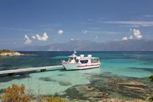 Excursion boat moored at jetty in clear turquoise water off the Plage du Loto, St-Florent, Haute-Corse, Corsica, France Excursion boat moored at jetty in clear turquoise water off the Plage du Loto, St-Florent, Haute-Corse, Corsica, France