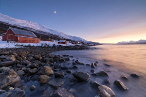 Lyngen Alps Norway Prints: Fiery sky at sunset and typical Rorbu, snowy peaks and frozen sea, Djupvik, Lyngen Alps