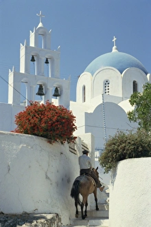 Figure on donkey passing church bell tower and dome Figure on donkey passing church bell tower and dome