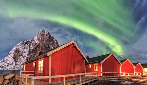 The green light of the Northern Lights (aurora borealis) lights up fishermans cabins The green light of the Northern Lights (aurora borealis) lights up fishermans cabins