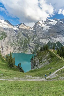 High angle view of two hikers walking on path above Oeschinensee lake, Bernese Oberland High angle view of two hikers walking on path above Oeschinensee lake, Bernese Oberland